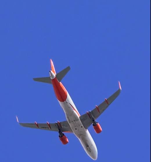Aircraft banking overhead against blue sky