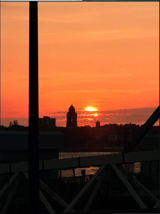 Deep orange sunset silhouette over a riverside skyline